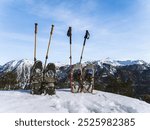 A pair of snowshoes and poles resting in deep snow against a backdrop of mountain ranges. Snowshoeing is popular in regions like the Alps, Rockies, Scandinavia, and the Pyrenees.