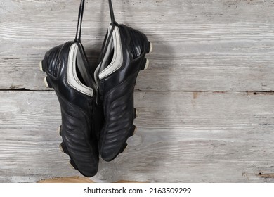 A Pair Of Soccer Boots Hanging On A Wooden Wall. The End Of The Football Career