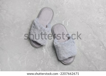 Pair of soft slippers on grey marble floor, top view