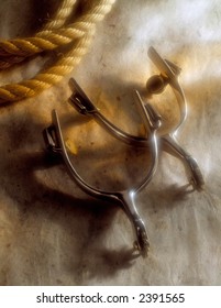 A pair of Spurs and a rope with warm lighting