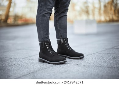 A pair of stylish dark brown leather boots paired with grey denim jeans captures the essence of modern urban fashion. - Powered by Shutterstock