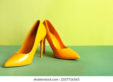 Pair of stylish high heeled shoes on green background