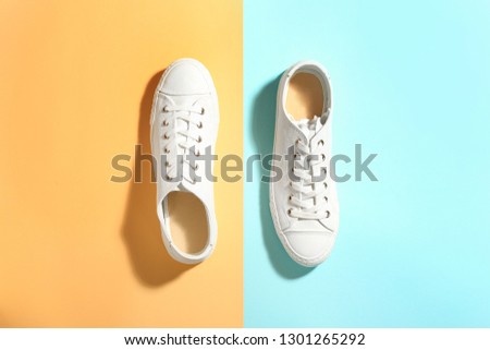 Pair of stylish sneakers on color background, top view