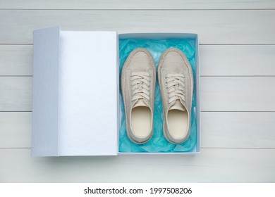 Pair Of Stylish Sport Shoes In Box On White Wooden Background, Top View