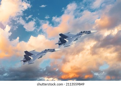 A Pair Of Tandem Military Fighter Jets Fly In The Sky Against The Backdrop Of Beautiful Clouds At Sunset