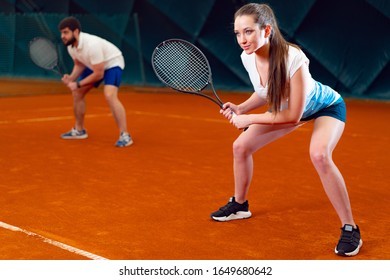 Pair of tennis players, man and woman waiting for service at indoor court