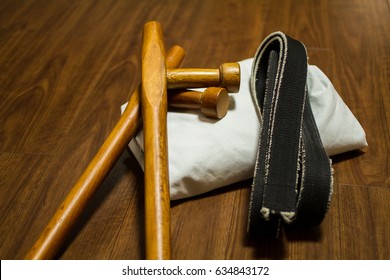 A Pair Of Tonfa (traditional Okinawa Kenpo Karate's Weapon), Black Belt (Karate, Judo, Kenpo, Jiu-Jitsu, Budo, Martial Arts, Taekwondo) And Gi (Japanese Martial Arts Uniform) On The Wood Floor