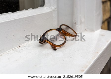 Pair of Tortoiseshell framed eye glasses folded and left on a white window ledge