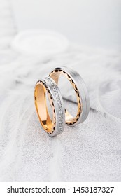 Pair of two tone gold wedding ring with matte surface and diamonds on white glossy background. Silver and gold wedding rings band with gemstones 