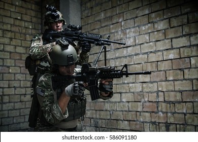 Pair Of US Army Rangers With Machinegun And Rifle Moving Along The Wall After Each Other On Military Mission