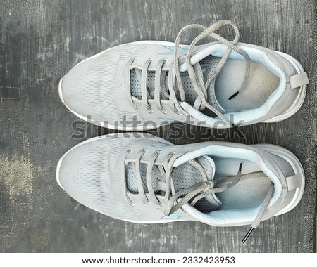 a pair of used grey couloured shoes on rough bench surface