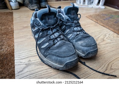 Pair Of Well Worn Blue Walking Shoes Or Trainers On A Wood Effect Porch Floor