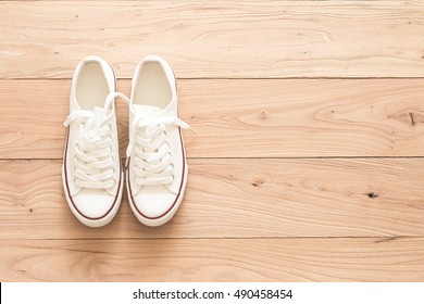 A Pair Of White Canvas Shoes On A Wooden