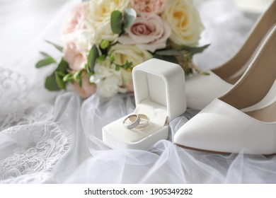 Pair Of White High Heel Shoes, Rings And Wedding Bouquet On Lace Veil