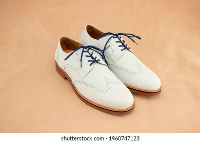 A Pair Of White Nubuck Bucks With A Bright Blue Laces On. This Fashionable Footwear Is A Classic For Mens Leather Shoes.