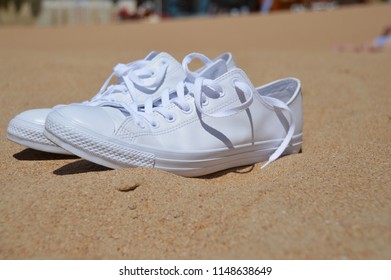 Pair of white trainers / sneakers on a sandy beach in the sunshine  - Powered by Shutterstock