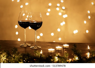 Pair of wine glasses on table with small candles and Christmas lights on background with copy space - Powered by Shutterstock