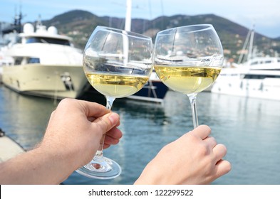 Pair of wineglasses in the hands against the yacht pier of La Spezia, Italy