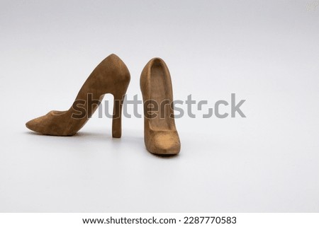 Pair of women's shoes made from wood. A beautiful high-heeled wooden shoes against white background. Handmade shoes for use in female concept 