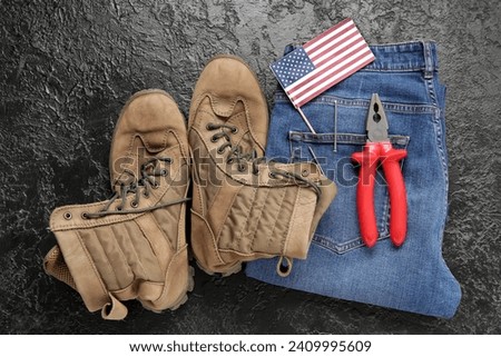 Pair of work boots, USA flag, jeans and pliers on black background. Labor Day celebration