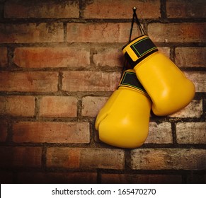 Pair of yellow boxing gloves hanging on a brick wall - Powered by Shutterstock