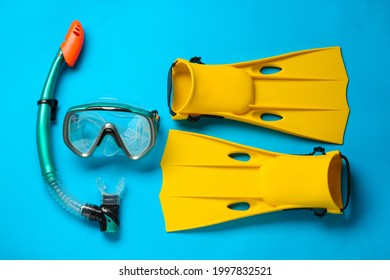 Pair of yellow flippers and mask on light blue background, flat lay