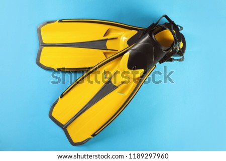 Pair of yellow flippers on color background, top view
