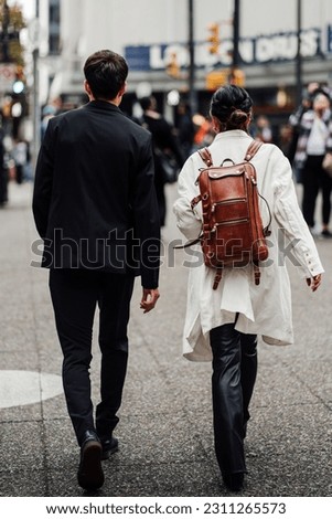 A pair of young adults in fashionable attire strolling through the vibrant downtown