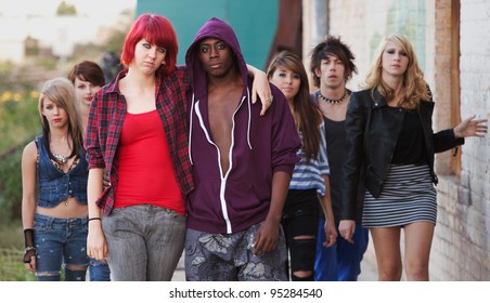 A Pair Of Young Punk Teens Pose Together As Their Friends Stay In The Background.