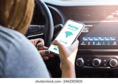 Pairing car with  phone.Woman using mobile device while driving. Connecting  car computer to her smartphone and app using wireless technology.