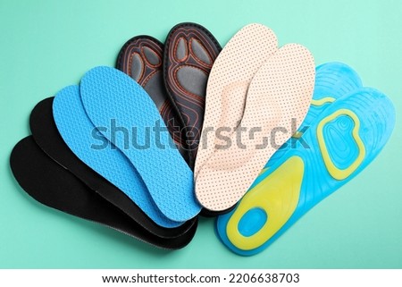 Pairs of different shoe insoles on turquoise background, flat lay