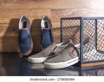 Pairs Of Men's Tennis Shoes On Black Table And Wooden Background With Grid