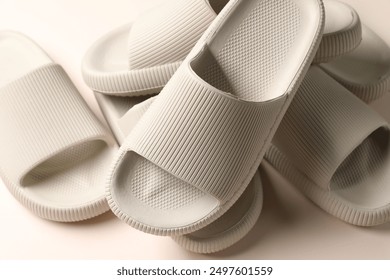 Pairs of rubber slippers on beige background, closeup