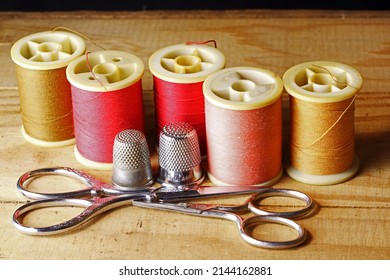 PAIRS OF SCISSORS AND THIMBLE WITH CRIMSON AND YELLOW HUED COTTON REELS