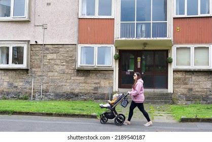 Paisley, Scotland, UK, August 7th 2022, Single Mother Walking Past Council Flats In Poor Housing Estate With Many Social Welfare Problems