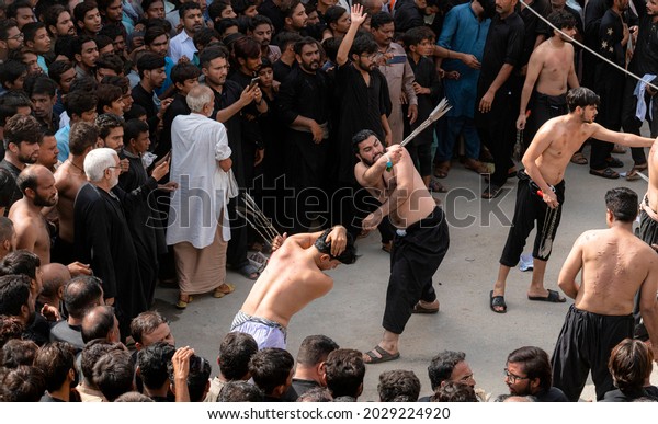 Pakistan , Multan - August 19, 2021: Ashura\
islamic holy day for shia muslims; mourning azadari rituals.\
Remembrance ceremonies for martyrdom of Imam Hussain. Ritual\
self-flagellation with\
chains