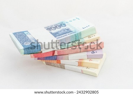 Pakistani banknote bundles stacked on white isolated background
