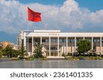 Palace of Culture or Opera on Skanderbeg Square in Tirana and the flag of Albania moving in the wind