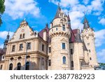 Palace in Moszna. Historic residence located in the Opole Voivodeship. Upper Silesia, Poland. Beautiful view of the castle against the blue cloudy sky. Tourist and Historical Attraction.