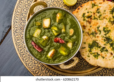 Palak Paneer Curry made up of spinach and cottage cheese, Popular Indian healthy Lunch/Dinner food menu, served in a Karahi with Roti Or Chapati over moody background. selective focus