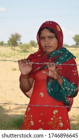 Palana, Bikaner, Rajasthan / India - September 01,2012: Beautiful Rajasthani young girl standing in barbed wireher farm in traditional Rajasthani dress in field 