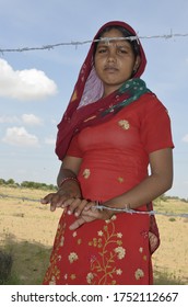 Palana, Bikaner, Rajasthan / India - September 01,2012: Beautiful Rajasthani young girl standing in barbed wireher farm in traditional Rajasthani dress in field 
