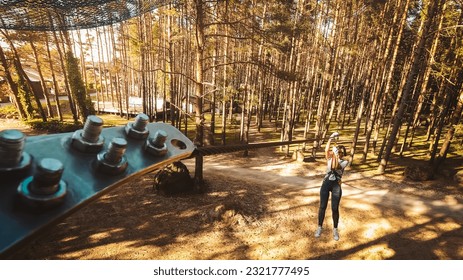 Palanga, Lithuania - 2023: young woman girl sliding along zipline in fir tree forest in summer. Lithuania adventure park in HBH. - Powered by Shutterstock