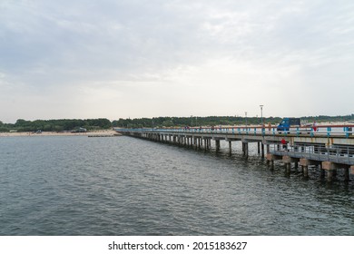 Palanga Lithuania - July 15 2021: Famous long pedestrian sea pier. Wooden bridge stretching into the sea. car with repair workers on the bridge.