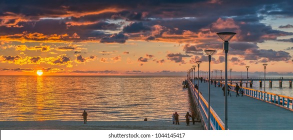 Palanga, Lithuania - October 03, 2013: Colorful sunset at a famous marine pier in the Baltic resort city of Palanga, tourists are walking and resting