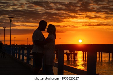Palanga, Lithuania. Silhouettes of a couple in love stand on a wooden pier by the sea at sunset