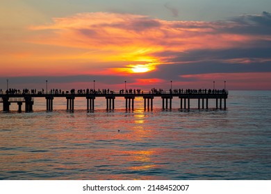 Palanga pier with people resting against the background of the sea sunset