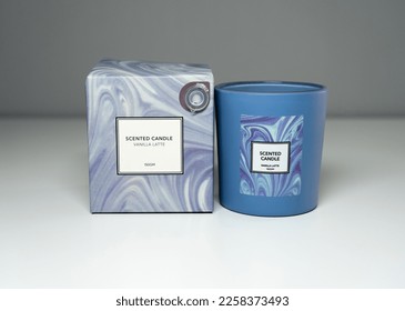 A pale blue packaging box and a blue glass tumbler of a vanilla latte scented candle. - Shutterstock ID 2258373493