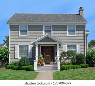 Pale Green Two Story Clapboard House With Shrubbery And Front Lawn In Summer