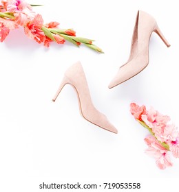 Pale pink female shoes decorated with pink gladioli on white background. Flat lay, top view trendy fashion feminine background. Beauty blog fashion concept.